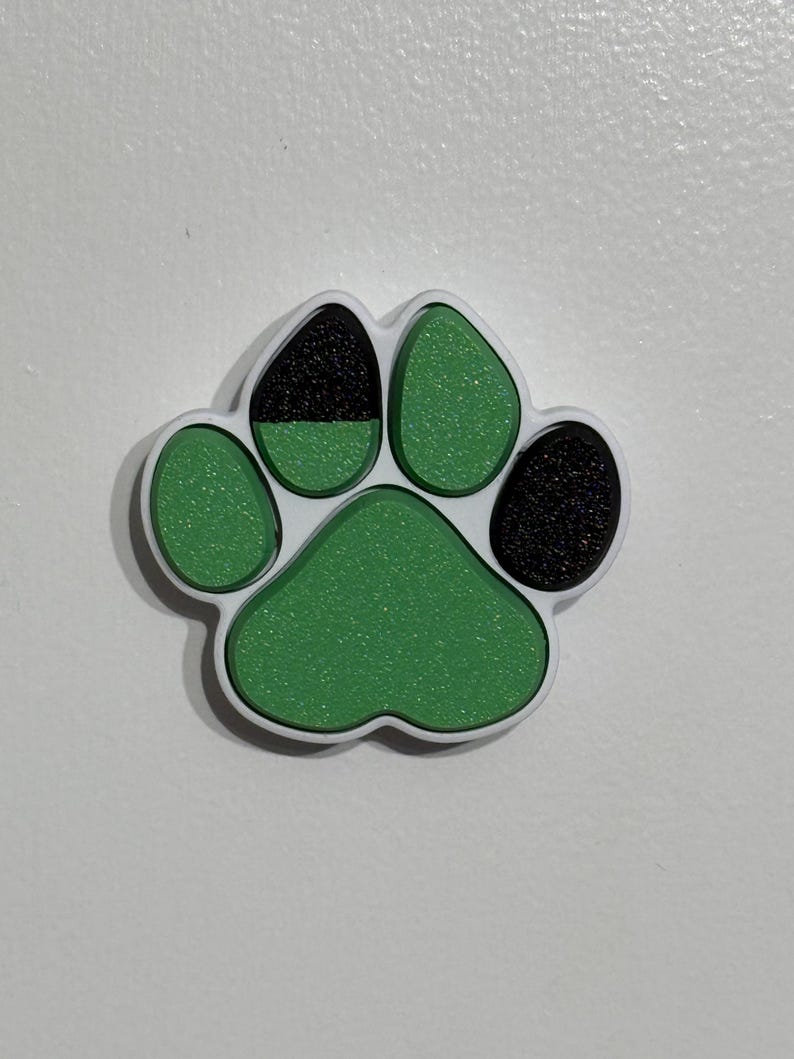 May include: A green and black paw print charm with a sparkly finish.