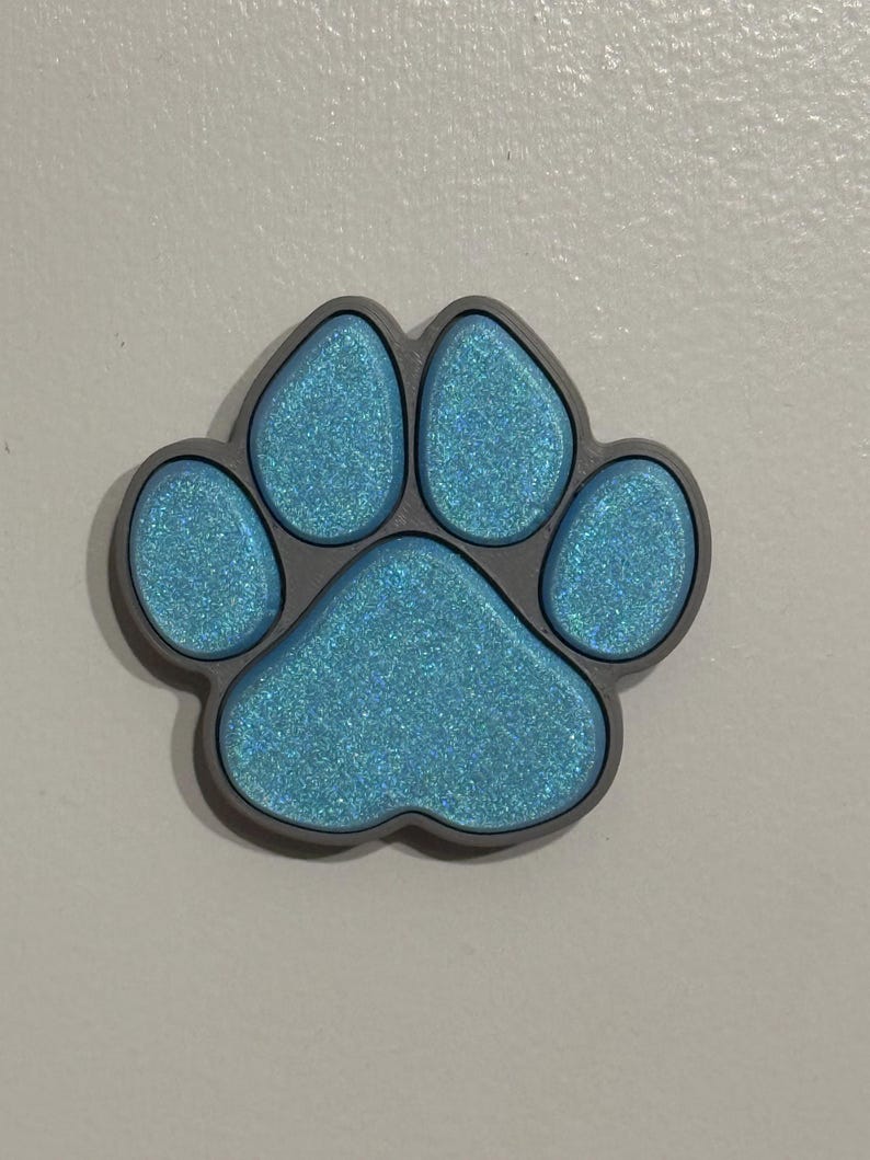 May include: A blue glitter paw print charm with a gray outline.