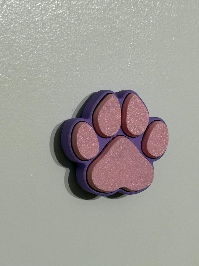May include: A purple paw print with pink raised details. The paw print is made of a soft, textured material.