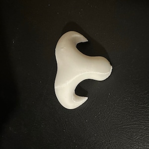 May include: A white 3D printed object with a unique, abstract shape. It has three points and a smooth, rounded surface.