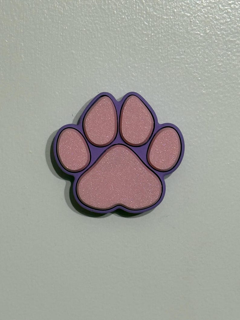 May include: A purple paw print with pink accents. The paw print is made of a textured material.