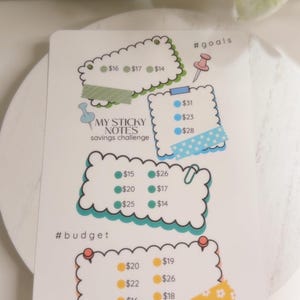 Könnte beinhalten: Eine weiße Spar-Challenge-Karte mit farbenfrohen, wolkenförmigen Abschnitten. Die Karte enthält den Text "MY STICKY NOTES savings challenge" und enthält Beträge wie 16, 17 und 14 $. Die Gesamtsumme beträgt 367 $.