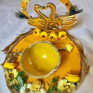 May include: A yellow and gold ring holder with a decorative swan design. The holder features a small bowl for the ring and is decorated with yellow flowers and gold trim.