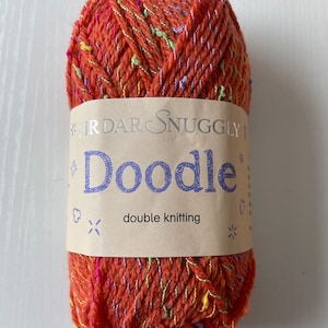 May include: A ball of orange yarn with multi-coloured flecks and a label that reads "Sirdar Snuggly Doodle double knitting".