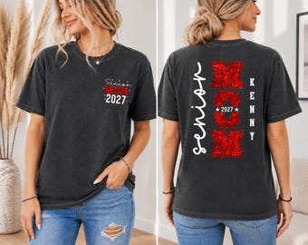 May include: Dark grey t-shirt with "Senior Mom 2027" printed on the front and back. The back of the shirt features the word "Senior" in white script and the word "MOM" in red glitter.