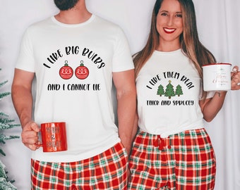 Może przedstawiać: Pasujące białe koszulki z tekstem o tematyce świątecznej. Jedna koszulka mówi "I like big bulbs and I cannot lie" z grafiką czerwonych ozdób. Druga mówi "I like them real thick and sprucey" z grafiką choinek. Obie są połączone z czerwono-kratkowanymi spodniami od piżamy.