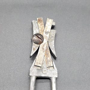 May include: Close-up of a vintage metal tool, possibly for cutting or shaping. The tool has a silver finish with some rust, a central screw, and the word "Mower" and "Shears" stamped on it. The tool has two handles.