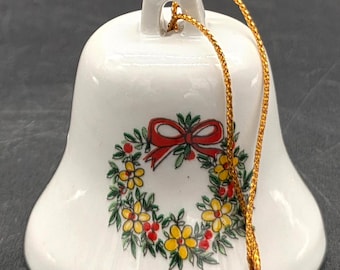 Campana navideña pequeña con guirnalda de flores amarillas y cinta roja.