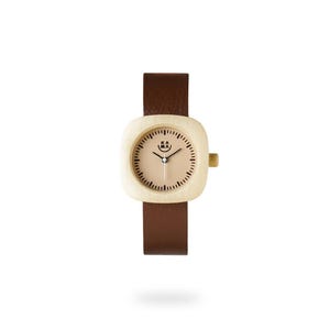 May include: A wristwatch with a light wood-colored square face and a brown leather band. The watch face has a light tan background with black minute markers and hands. The watch has the text "KA MA" on the face.