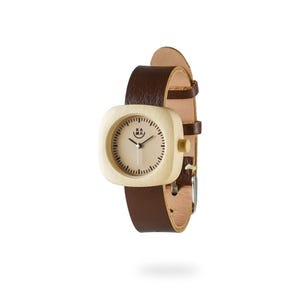 May include: A square-faced wristwatch with a light wood grain case and a tan face. The watch has a dark brown leather band. The watch face has black minute markers and the brand name "KA MA" printed on the face.