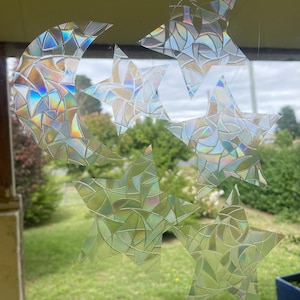 May include: A set of iridescent window clings featuring a crescent moon and five stars. The clings are made of a clear, textured material that creates a stained glass effect.