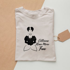 Pu&ograve; includere: Una maglietta bianca con una silhouette nera di una donna con una corona e il testo "Villains Have More Fun".