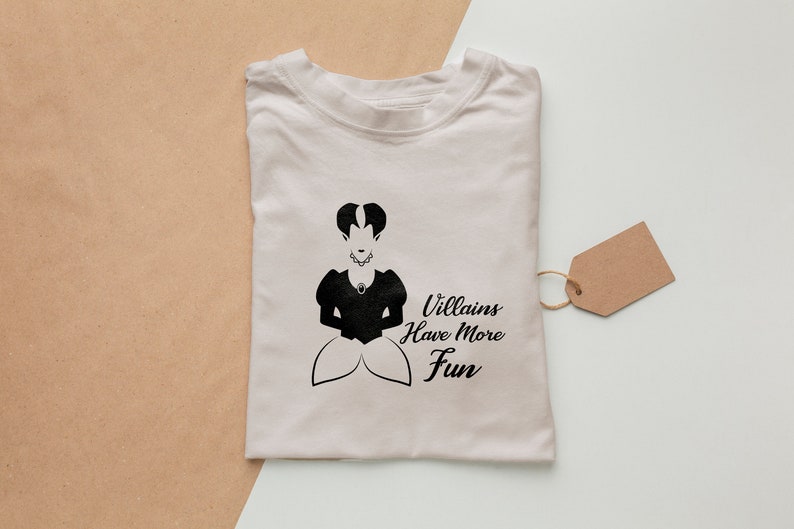 Pu&ograve; includere: Una maglietta bianca con una silhouette nera di una donna con una corona e il testo "Villains Have More Fun".