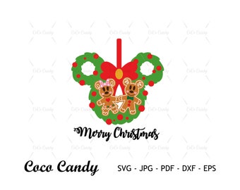 Pode incluir: Uma coroa verde em forma de orelhas do Mickey Mouse com um laço vermelho e dois biscoitos de gengibre no centro. Os biscoitos são um homem de gengibre e uma mulher de gengibre. O texto "Merry Christmas" está escrito abaixo da coroa.