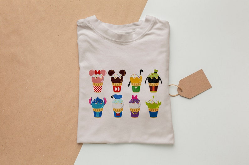 Puede incluir: Camiseta blanca con un gr&aacute;fico colorido de varios personajes de Disney en forma de conos de helado. Los personajes incluyen Mickey Mouse, Minnie Mouse, Stitch y otros.