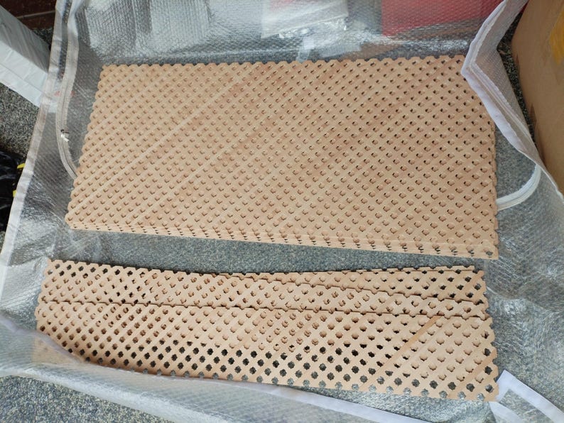 a clear plastic bag containing two wooden boards with a lattice pattern. The boards are arranged in a way that they appear to be folded or stacked on top of each other.