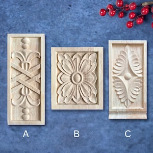 May include: Three rectangular light-colored wood carvings labeled A, B, and C. Carving A features a vertical symmetrical pattern with spheres. Carving B displays a central floral motif. Carving C shows a vertical leaf-like design with a center dot.