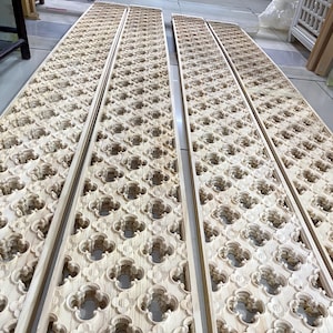 Può includere: Diversi pannelli di legno non rifiniti con un motivo a quadrifoglio ripetuto. I pannelli sono rettangolari e sembrano far parte di un progetto decorativo più ampio. Il legno ha un colore chiaro naturale e l'intricato disegno è intagliato ovunque.