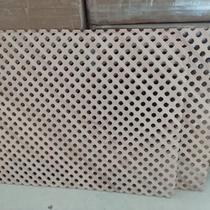 a close-up view of a wooden lattice with a repeating pattern of small holes or squares, creating a textured and intricate design.