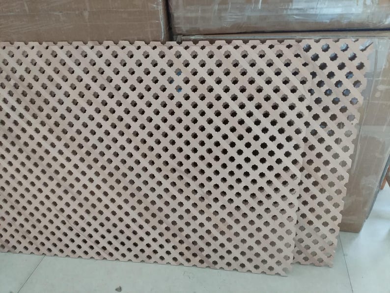 a close-up view of a wooden lattice with a repeating pattern of small holes or squares, creating a textured and intricate design.