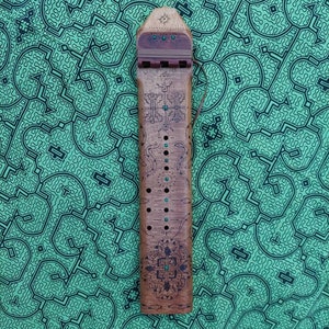 May include: A wooden musical instrument with a carved design and turquoise accents. The instrument has a series of holes along the side and a string attached to the top.