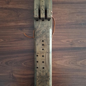 May include: A wooden flute with intricate carvings and a leather strap. The flute has multiple holes and a decorative design at the top.