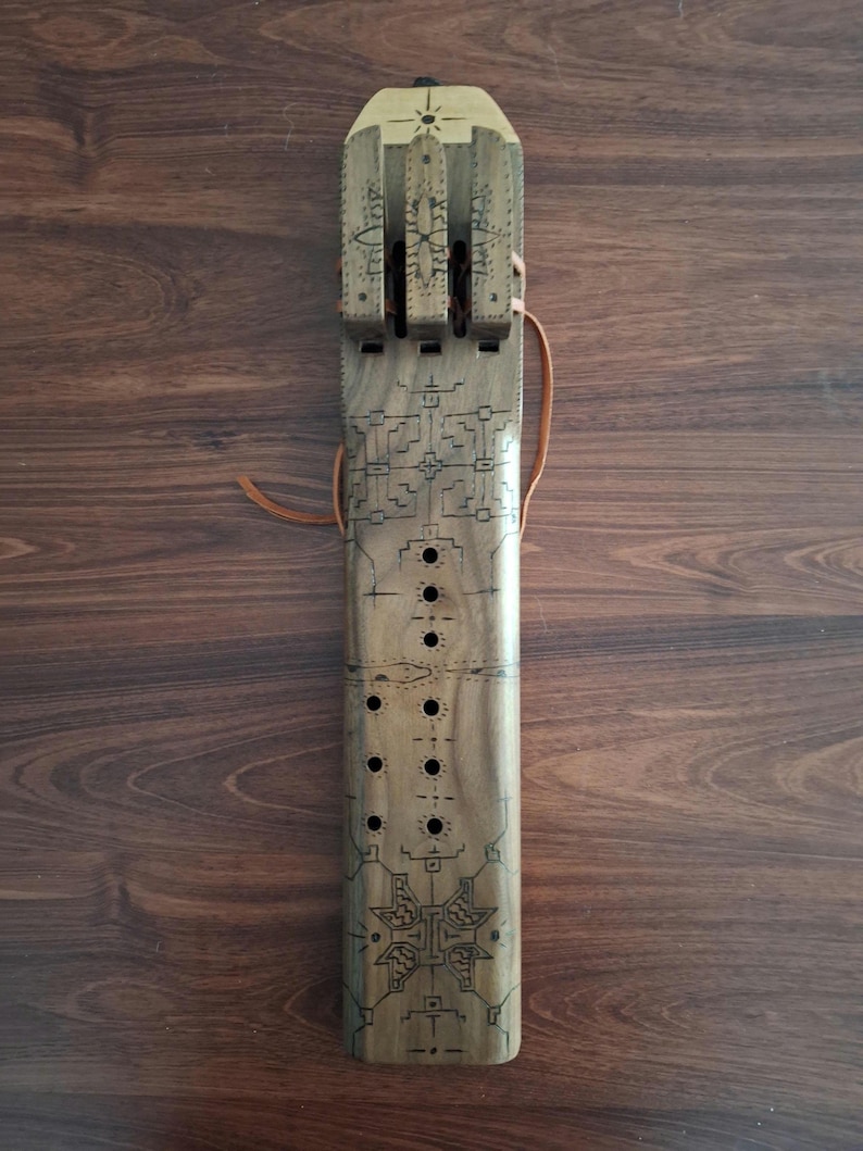 May include: A wooden flute with intricate carvings and a leather strap. The flute has multiple holes and a decorative design at the top.