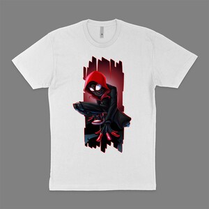 May include: White t-shirt with a graphic of Miles Morales, the Spider-Man character from the movie Spider-Man: Into the Spider-Verse, in a red hooded suit and black pants. He is crouched down with his arms outstretched, as if he is about to jump.