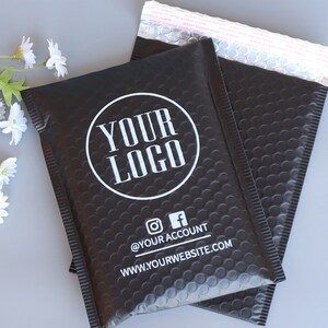 May include: Two black padded mailing envelopes with a white circle logo that says "YOUR LOGO" and the text "@YOURACCOUNT" and "WWW.YOURWEBSITE.COM" below the logo.