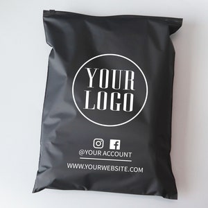 Op de afbeelding: Zwarte poly mailer met een witte cirkel met de tekst "YOUR LOGO" en de tekst "@YOUR ACCOUNT" en "WWW.YOURWEBSITE.COM" onder de cirkel.