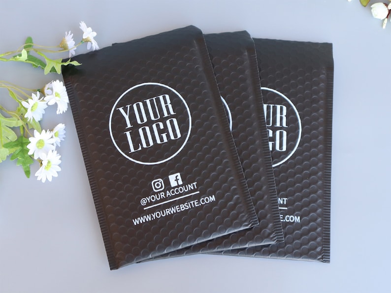 May include: Three black padded mailing envelopes with a white circle logo that says "YOUR LOGO" and the text "@YOUR ACCOUNT" and "WWW.YOURWEBSITE.COM".