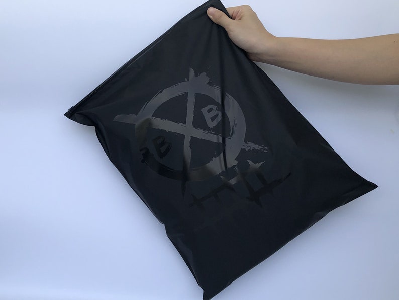 Op de afbeelding: Zwarte trekkoordtas met een wit logo met de tekst "REBEL HATE" in een gestileerd lettertype.