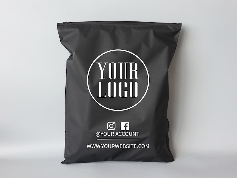 Op de afbeelding: Zwarte poly mailers met een witte cirkel met de tekst "YOUR LOGO" en de tekst "@YOUR ACCOUNT" en "WWW.YOURWEBSITE.COM" onder de cirkel.