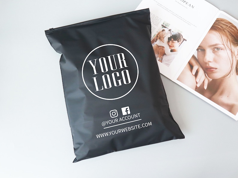 Op de afbeelding: Zwarte poly mailer met een witte cirkel met de tekst "YOUR LOGO" en de tekst "@YOUR ACCOUNT" en "WWW.YOURWEBSITE.COM" onder de cirkel.