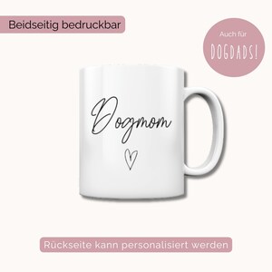 Puede incluir: Taza de cer&aacute;mica blanca con el texto "Dogmom" en escritura cursiva negra y un peque&ntilde;o coraz&oacute;n debajo. La taza est&aacute; impresa por ambos lados y la parte posterior se puede personalizar.