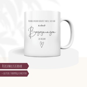 Puede incluir: Taza de cerámica blanca con texto negro que dice "Verabschieden bedeutet auch, sich auf neue Begegnungen zu freuen!" con un pequeño símbolo de corazón. La taza está sobre una superficie blanca. El texto "PERSONALISIERBAR" y "+ WEITERE FARBMÖGLICHKEITEN" están en un rectángulo marrón debajo de la taza.
