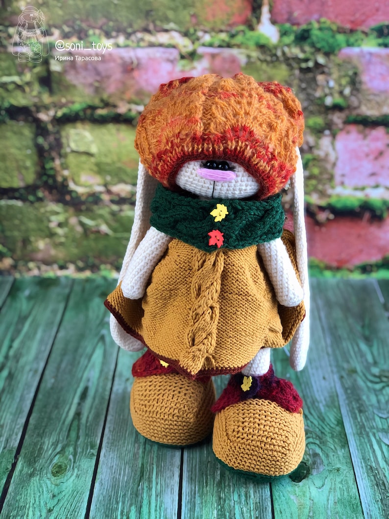 K&ouml;nnte beinhalten: Ein geh&auml;keltes H&auml;schen, das einen braunen und orangen Hut, einen gr&uuml;nen Schal und ein gelbes Kleid tr&auml;gt. Das H&auml;schen steht auf einer gr&uuml;nen Holzoberfl&auml;che. @soni_toys Ирина Тарасова