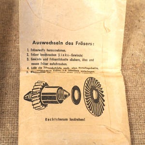 May include: A vintage paper instruction sheet, open to reveal a diagram of a tool's components. The text, in German, details the process of changing the tool's cutter. The paper has a worn, aged appearance, with a beige color.