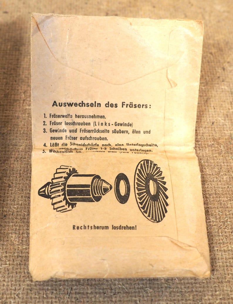 May include: A vintage paper instruction sheet, open to reveal a diagram of a tool's components. The text, in German, details the process of changing the tool's cutter. The paper has a worn, aged appearance, with a beige color.