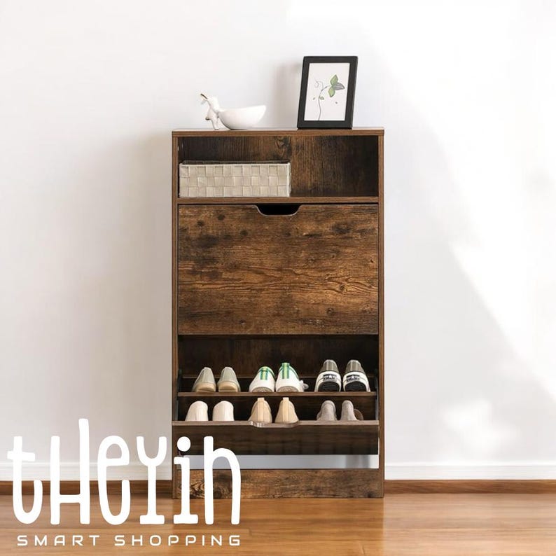 K&ouml;nnte beinhalten: Ein braunes Schuhregal aus Holz mit einer Schublade und Regalen. Das Schuhregal hat eine gealterte Holzoptik und ist f&uuml;r die Aufbewahrung mehrerer Schuhpaare konzipiert. Das Schuhregal steht auf einem Holzboden.