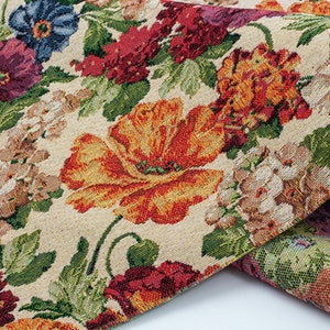 Pode incluir: Um close-up de um tecido com um padrão floral. O tecido apresenta uma variedade de flores, incluindo papoulas, rosas e margaridas. As flores estão em tons de vermelho, laranja, amarelo, rosa e azul. O tecido é de cor creme com uma textura sutil.
