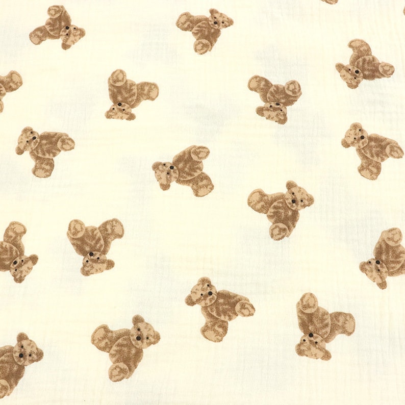 May include: A white fabric with a repeating pattern of brown teddy bears. The bears are all facing the same direction and are in various positions.
