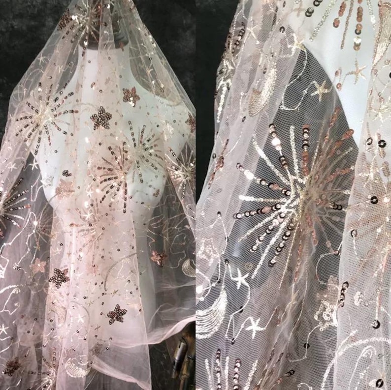 May include: Pink sheer fabric with gold and silver sequins in a star, moon, and firework design.