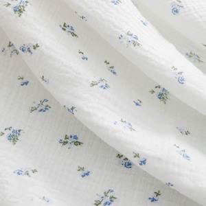May include: White fabric with a small blue floral pattern.