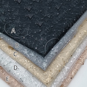 May include: Five layers of sheer fabric with a star-shaped pattern and sequins. The fabric is black, gray, beige, white, and pink.