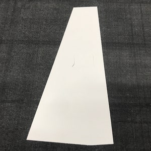 May include: A white, triangular-shaped cardboard sign with a cut-out hole in the center.