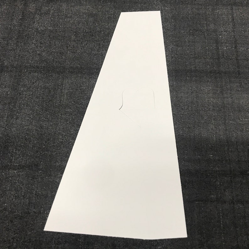 May include: A white, triangular-shaped cardboard sign with a cut-out hole in the center.