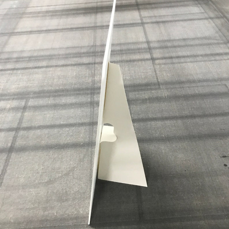 May include: White cardboard sign with a fold-out easel stand. The stand is made of a single piece of cardboard that folds to create a triangular support.