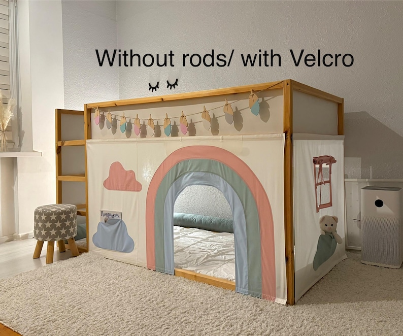 Puede incluir: Un marco de cama de madera con una tienda de tela blanca con un arco iris, nubes y una pancarta colgante. El texto "Without rods/ with Velcro" est&aacute; encima de la cama. Un peque&ntilde;o taburete con un patr&oacute;n de estrellas est&aacute; cerca.