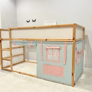 以下が含まれることがあります： 薄い青とピンクのテントのような天蓋が付いた木製の二段ベッド。天蓋には白い枠とピンクの縁取りのある小さな窓があります。ベッドには側面に梯子があります。